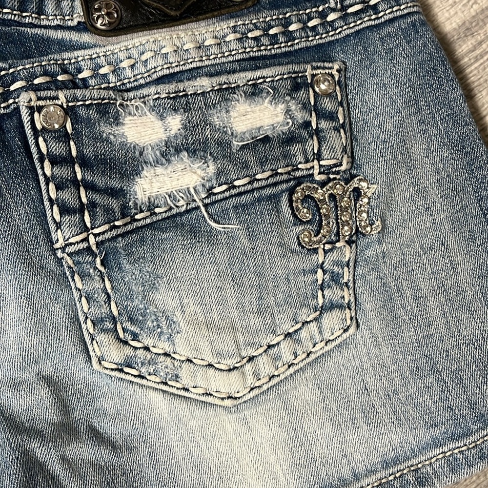 Womenโs Light Blue Distressed Denim Shorts with Embellished 'M'
